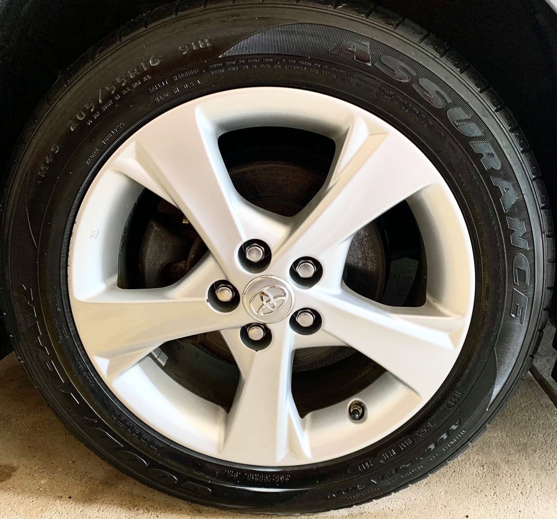 The same alloy wheel after cleaning, with a bright face, clean lug seats and a black dressed tire